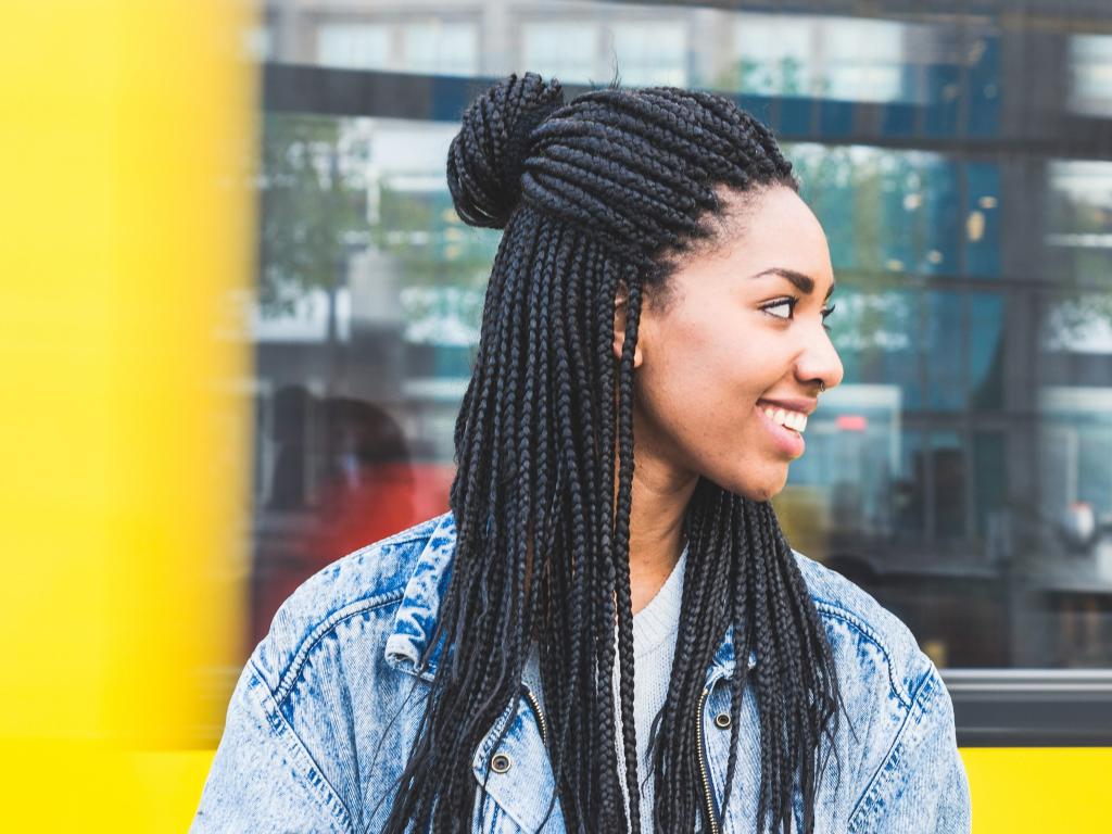 Woman in front of transit turning head and smiling at person off screen