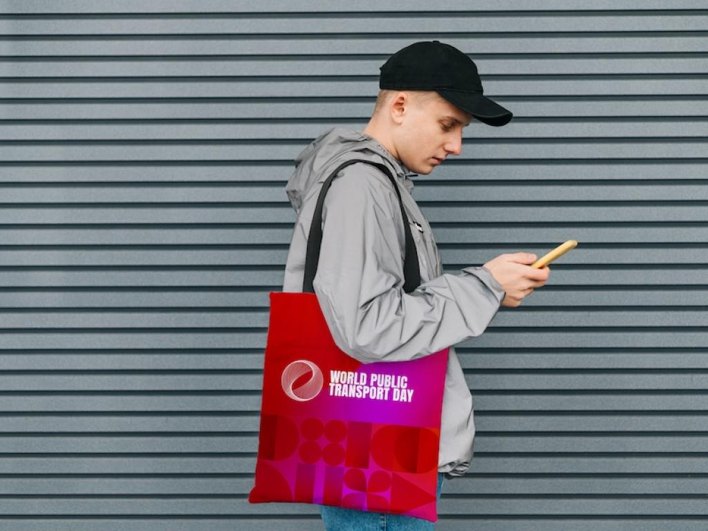 Man with branded tote bag looking at mobile phone